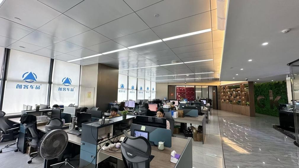 A wide view of the CKCP office with people at desks and the company brand on the windows